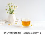 Chamomile tea in a transparent mug with natural small chamomile flowers