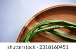 Small photo of Close up isolated flat lay long bean vegetables or Vigna unguiculata ssp sesquipedalian on a wooden tray. Selective focus