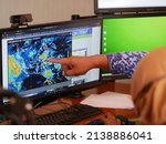 Small photo of Tarakan, Indonesia. 03-25-2022. Indonesians meteorologists monitor radar displays. Weather forecast in a office.