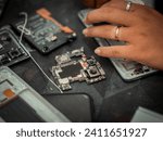 Small photo of Close-up shot showing the process of cell phone repairing. Technician repairing the phone. Fixing smartphone and upgrade mobile details. Disassembled cell phone. Internal components of a smartphone.