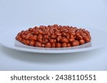 Fried groundnut, Goober or Monkey Nut, or Arachis hypogaea. On a white plate, isolated on white background