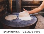 Small photo of Mexican woman torturing corn mace on a metate and wood stove to make homemade tortillas