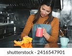 Small photo of Smiling Latina worker, wiping the bar of spilt milk with a cloth, holding the claw in the other hand.