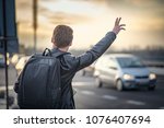 Small photo of Young man tourist in a foreign city trying to hail a cab, holding a map to navigate himself