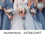bride in wedding dress surrounded by bridesmaids in light blue dresses holding hydrangea bouquets 