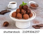 Chocolate Coffee Truffles. Assorted chocolate candy balls served on white serving stand with cocoa, cup of coffee and chocolate pieces on background. 