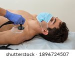 Small photo of woman physiotherapist with mask does a diathermy to a man whith a chronic pain