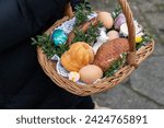 Small photo of Woman holding Easter basket for blessing in a church. Traditional woven wicker Paschal basket filled with various food, ready to be blessed by a priest as part of the Easter tradition.