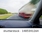 Small photo of Car is going to overtake white / red truck on Dutch/European two-lane highway at high speed. Dashboard view with motion blur.