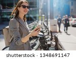 Happy stylish woman taking bike via bike renting services in the city center, Happy smiling student using bike sharing app on smart phone outdoor