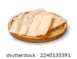 Baking paper on wooden board isolated. Round board with crumpled pieces of brown parchment or baking paper on white background. Design element.