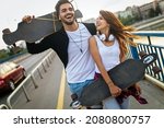 Portrait of young couple with skateboard and longboard having fun outdoors