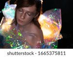 Small photo of Artistic portrait of a beautiful girl with silver make-up. With a luminous dress from a color film