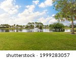 Lake with fountains in the middle of a residential complex in Miami. Trees, grass and a blue sky.