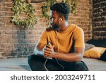 Small photo of Black young man listening to music otr telecoference on mobile phone. Technologies and online social media