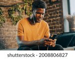 Small photo of Black young man listening to music otr telecoference on mobile phone. Technologies and online social media