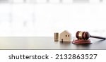 Small photo of Real estate sale auction concept - gavel, house model and stack of coins on wooden table, banner background.