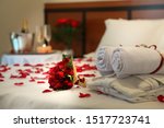 towels, bathrobes, flower bouquet and red petals on a double bed