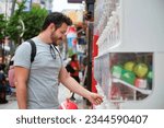 Small photo of Latin tourist buying a toy capsule at gashapon vending machine in Tokyo, Japan.