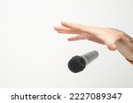 Small photo of Caucasian male's hand dropping the mic, stretched hand and a microphone soft focus close up isolated on white background