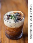 Small photo of alcoholic drink decorated with rosemary, orange and roasted safflower beans. carajillo