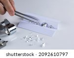 Small photo of Closeup of diamonds at workplace of diamond dealer assessing quality and color of polished diamonds using various tools.