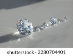 Small photo of Close up of diamonds of different cuts and sizes on light background with shadows.