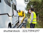 Caucasian man waiting tow truck motor home on the highway with a reflective vest and checking the vehicle
