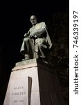 Small photo of Statue of Alois Jirasek, Prague, Czech Republic / Czechia - sculpture of famous czech writer, author, prosaic and novelist. Monument is lit by light during night (dramatic light, deep blacks)