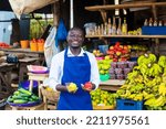 young exciting fruits salesman standing in front of a colorful fruits background holding up apples
