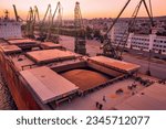 Aerial of wheat loading to bulker ship cargo hold at sea grain elevator in sea port at sunset. Black Sea Grain Initiative and grain deal