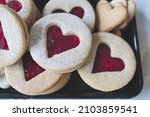 Macro image of Linzer cookies with heart cut out shape. Red raspberry jam filling. Valentines day, love and romance food concept image.