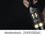 March 14th. Day 14 of month, Calendar date. Hands hold bottle of red wine with a calendar date on label.  Spring month, day of the year concept