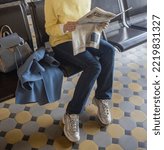 Small photo of St. Petersburg, Russia, September 21, 2022, Vitebsky railway station, depicts a girl in a yellow sweater, blue coat and jeans with a newspaper in her hands. Fake news, gossip, discredit