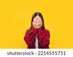 Women are using hand to close eyes while feeling sadness over isolated yellow background.