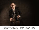 Small photo of Ghost of Jacob Marley, Scrooge ex-business partner, chained with a padlock, carrying treasure chests and keys, in front of a stone portal