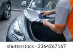 Small photo of Abu Dhabi, United Arab Emirates - September 20th, 2023 - Car wrapping specialist putting vinyl foil or film on car. Protective film. Applying a protective film with a squeegee