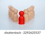 Small photo of Red wooden figure representing a leader leading other figure. Leadership concept