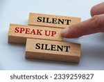 Finger pushing wooden block with red written text speak up. Courage and speak up concept