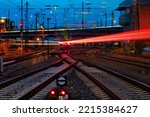 Blue hour at the main station of Hagen Westphalia Germany with railway infrastructure technology, signals, crossings, catenary, glistening tracks, switches at twilight. Train lights in motion. 