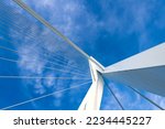 Steel cables and white metal construction from frog perspective with blue sky. Diagonal lines and bridge details with vanishing point.
