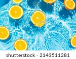 Creative summer composition made of sliced orange in transparent pool water. Refreshment concept. Healthy refreshing drink theme. Top view