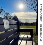 Small photo of DUBUQUE, IOWA, November 24, 2021–Closeup photo of backlit wooden dedication bench at Dubuque County Humane Society Dog Park on cloudy blue sky sunny Fall day.