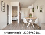 Stylish dining area in studio living room with table and chairs and decorative accessories overlooking the outdoor bathroom and bedroom. Concept of interior for a small apartmen