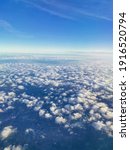 Small photo of Travel concept. A beautiful view from an airplane on white voluminous fluffy clouds against the background of a bright blue sky, city skyscrapers below, top view, vertical frame