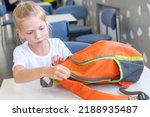 A student girl puts stationery in a backpack. A child zips up a school bag. Back to school. Self-assembly of a school backpack.