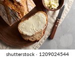 Artisan sliced toast bread with butter and sugar on wooden cutting board. Simple breakfast on grey concrete background. Top view