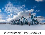 Oil pump jack under the blue sky with clouds winter working. Oil rig energy industrial machine for petroleum in the sunset background for design. Nodding donkey