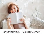 A healthy young woman wearing a sleeping mask after a good night's rest. A happy red-haired lady feels cheerful, full of joy, full of energy in the early morning, reading a book. Crazy home