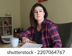 Small photo of Dispassionate, silent, stressed dark-haired businesswoman working in office with laptop, reports and cup of coffee on coffee break. Depression at terrible work, frustration and anxiety, feel unwell